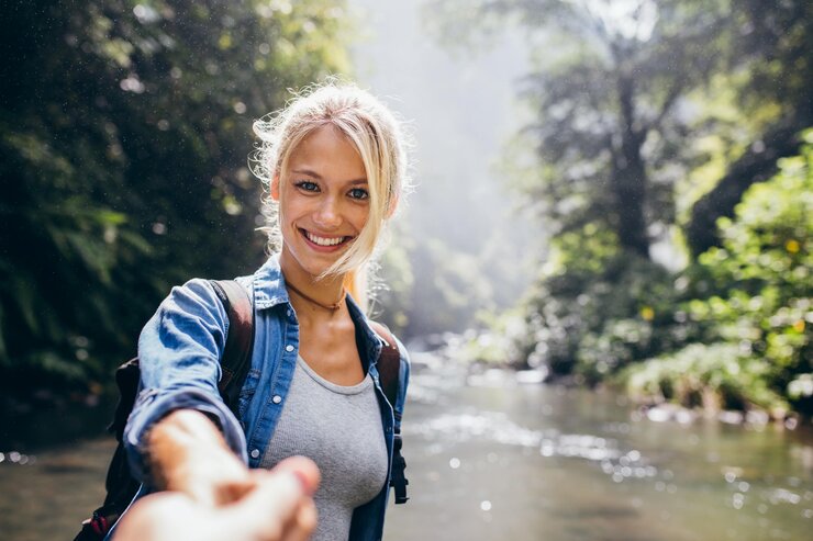 Teenager Mädchen schaut in die Kamera und hält die Hand ihres Partners auf Naturwanderung, der hinter der Kamera steht. | © © iStock.com | Jacob Ammentorp Lund