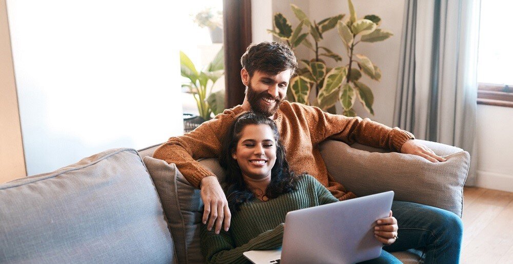 Aufnahme eines jungen Paares mit einem Laptop, während es sich zu Hause auf dem Sofa entspannt | © © iStock.com | PeopleImages